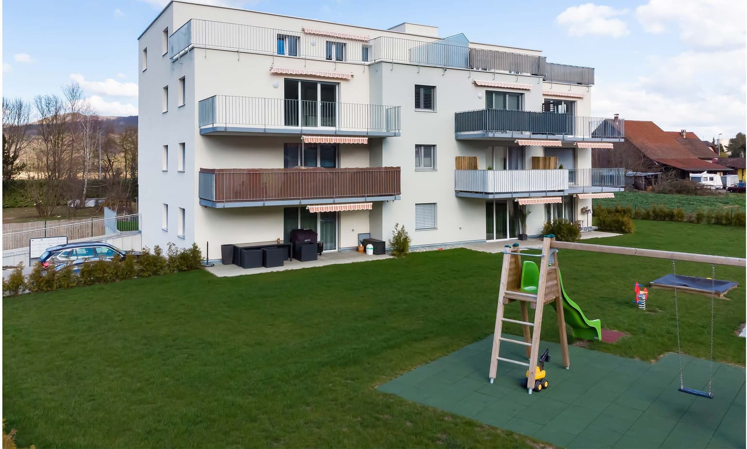 Westansicht des bestehenden Mehrfamilienhauses Weiherweg 9 mit Balkonen, Garten und Spielplatz